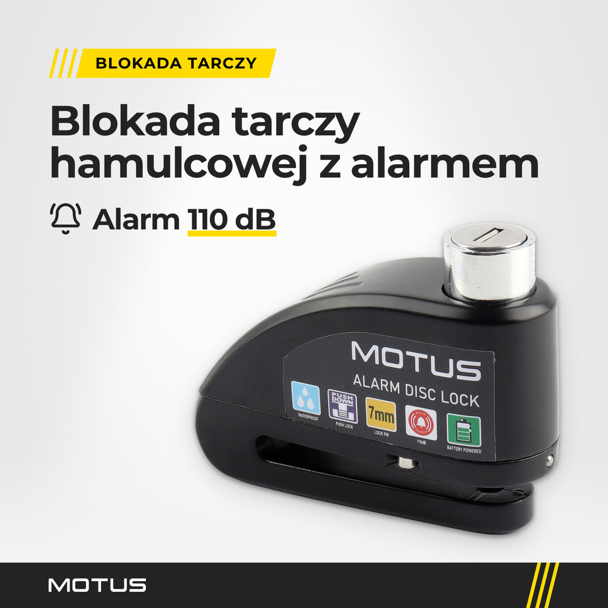 Blokada tarczy z alarmem MOTUS Alarm Lock w jasnym studiu, widok 3/4: obudowa z naklejką MOTUS, srebrna wkładka zamka i szczelina na tarczę.