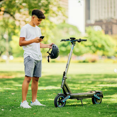 MOTUS Scooty 10 Max - z użytkownikiem sprawdzającym aplikację w telefonie
